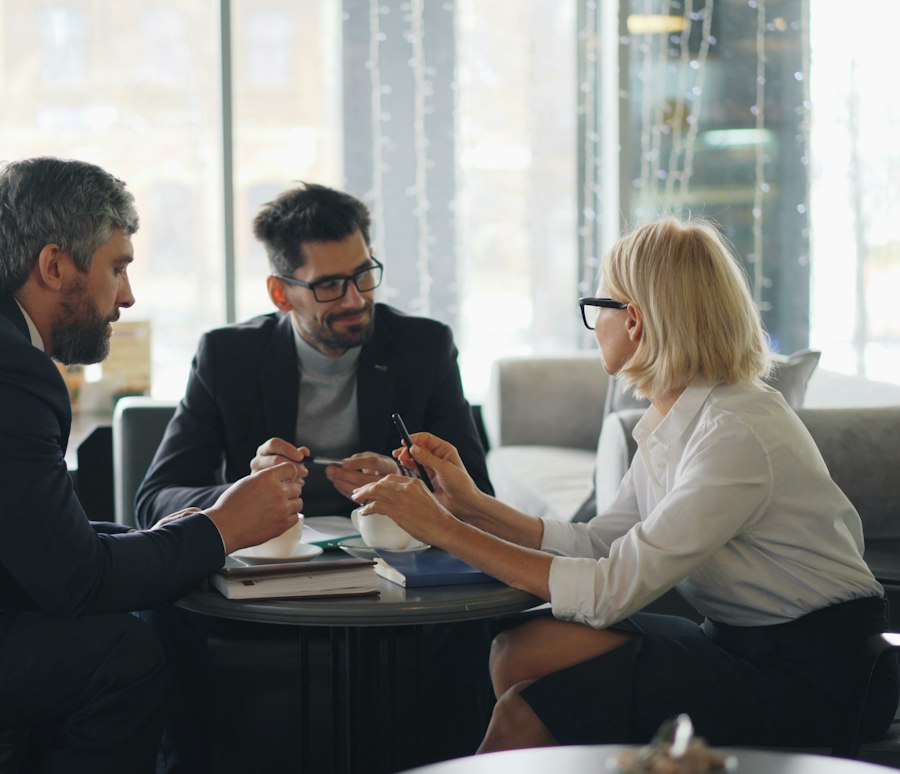 Reunião de trabalho entre três pessoas em uma mesa de escritório