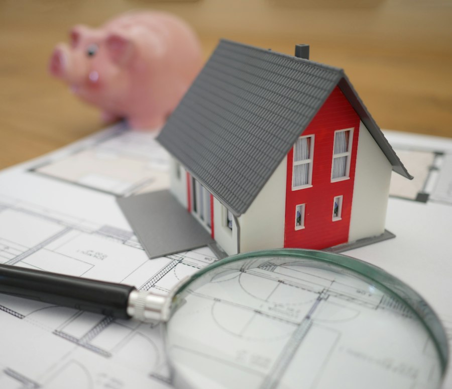 Miniatura de casa e lupa sobre a planta de um imóvel